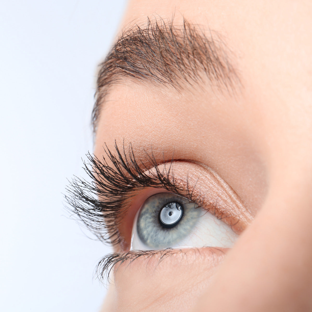 A close-up image showing the beautifully curled and lifted eyelashes of a person with blue eyes. The lashes are thick, long, and voluminous, emphasizing the natural effect achieved after using the Wow Lash Pro Heated Eyelash Curler.