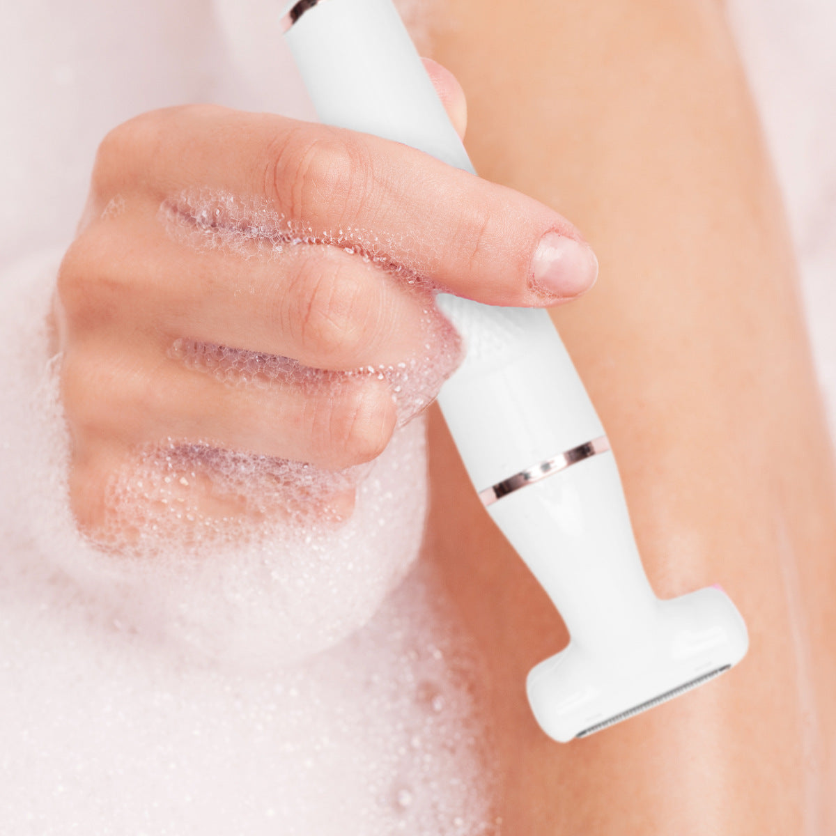 A close-up image of the Lady Shaver Bikini Trimmer being used in a wet environment, with bubbles around the hand holding the device. This demonstrates its waterproof capabilities, ideal for safe use during showers or baths.