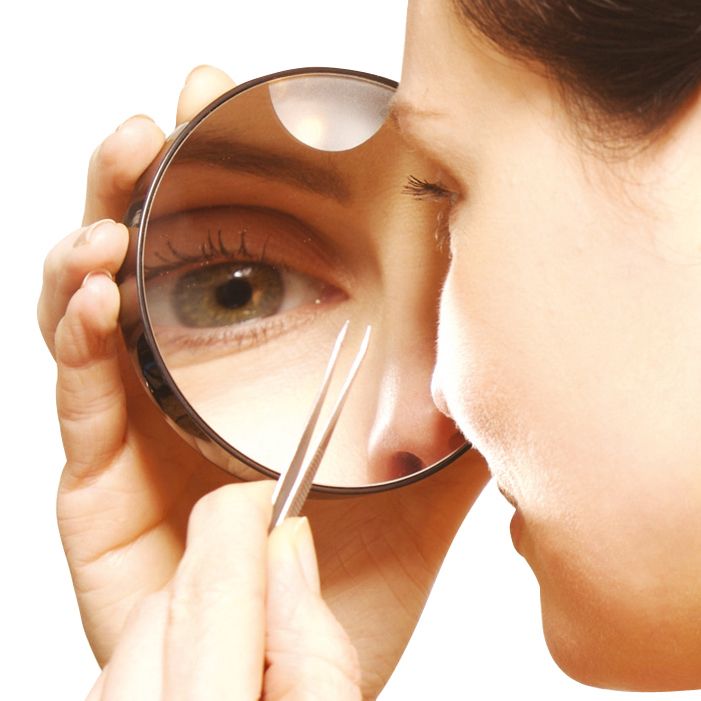 lady using x10 magnification mirror to tweeze eyebrows 